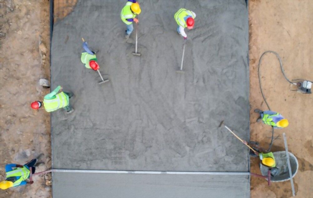 concrete contractors working hand in hand to finish this plain concrete driveway in Scottsdale AZ